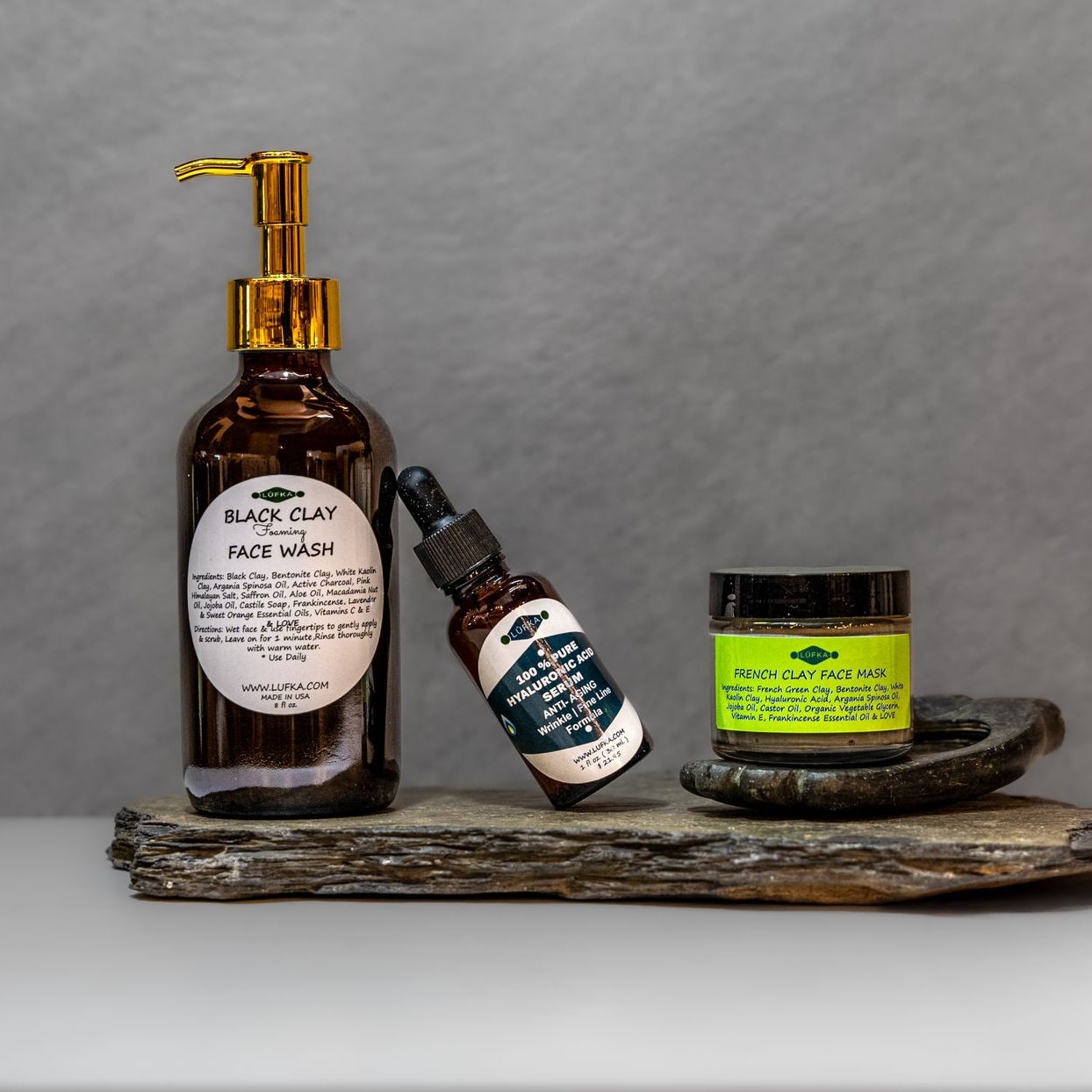 A skincare bundle featuring a foaming face wash, facial toner, and face mask on a wooden surface with a gold-colored pump and a green bottle.